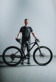Lächelnder Mann posiert mit seinem schwarzen Mountainbike und präsentiert so den Outdoor-Radfahr-Lifestyle und Fitness.