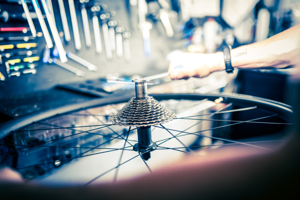 Nahaufnahme eines Fahrradmechanikers, der in einer Werkstatt mit Werkzeugen ein Fahrradrad repariert; Fahrradwartung.