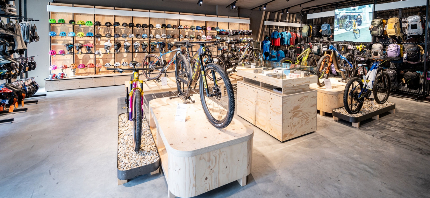 Fahrradladen-Interieur mit ausgestellten Mountainbikes, Helmen, Rucksäcken und Fahrradausrüstung.