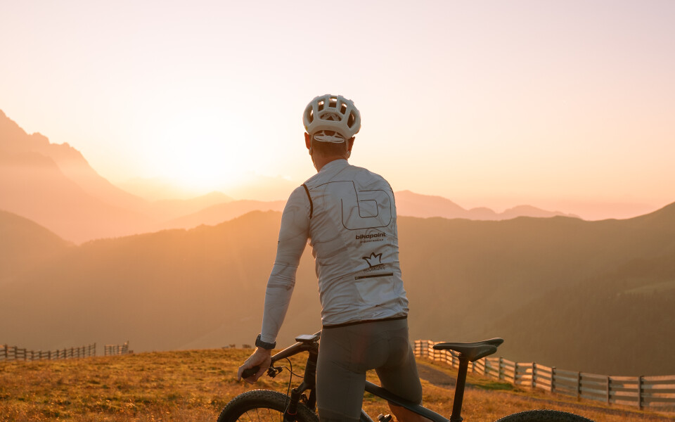 Radfahrer mit Mountainbike genießt den Sonnenuntergang in alpiner Landschaft. Outdoor-Abenteuerreise.