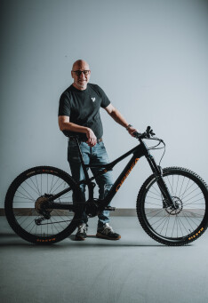 Mann mit Mountainbike. Radfahrer posiert mit seinem schwarzen vollgefederten Fahrrad. Radsport-Lifestyle.