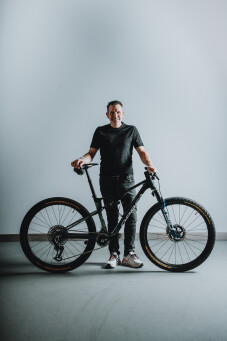 Mann posiert mit schwarzem Mountainbike. Radfahrer mit vollgefedertem Fahrrad für Offroad-Abenteuer.